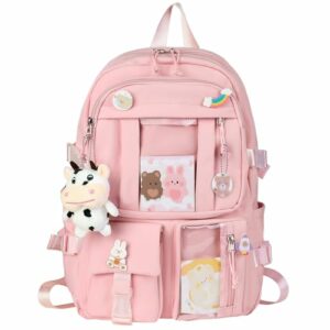 Mochila rosa con pines y accesorios kawaii, incluyendo un colgante de peluche con forma de vaca y tarjetas de dibujos animados.