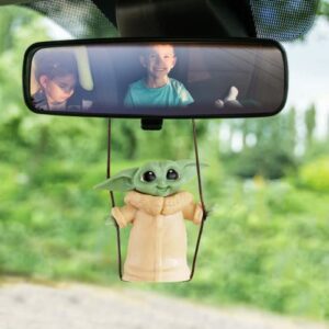 Colgante decorativo para retrovisor de coche con figura de personaje verde en un columpio.